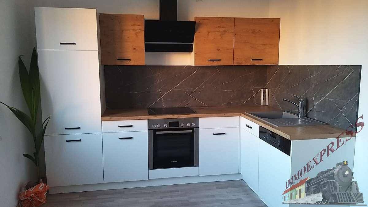 Moderne L-förmige Küche mit weißen und holzfarbenen Schränken, Kochfeld, Backofen und Spülbecken.