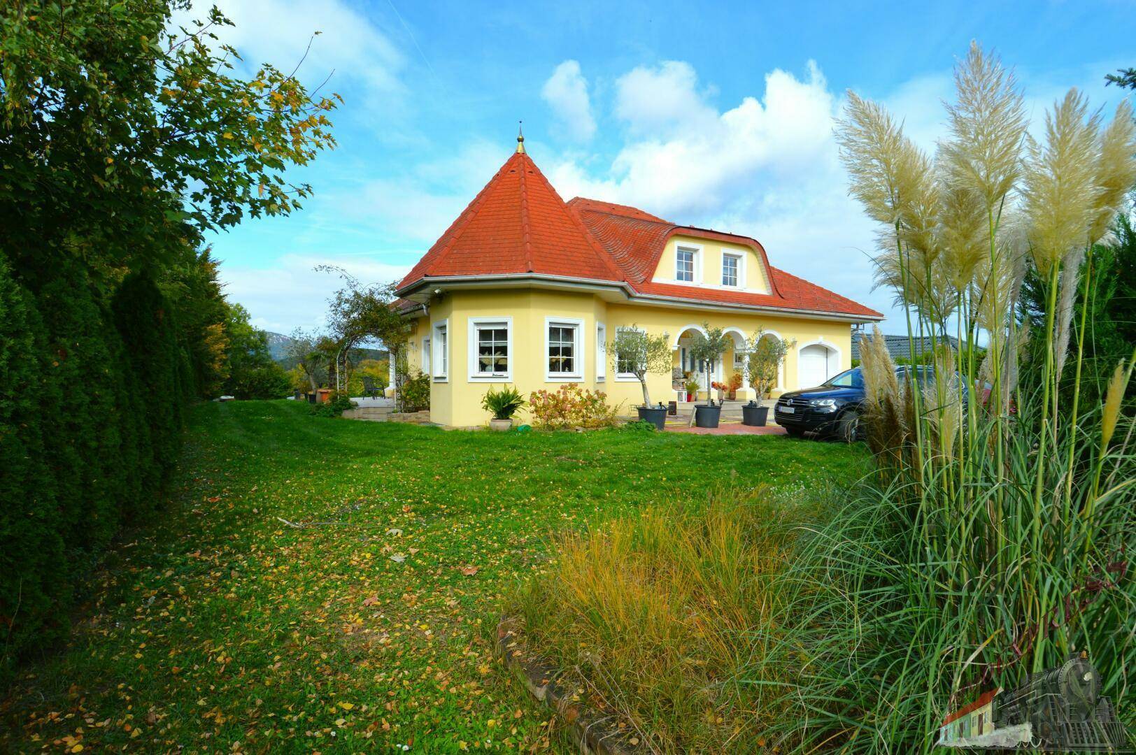 Charmantes Einfamilienhaus mit gelber Fassade, rotem Dach und großem Garten.
