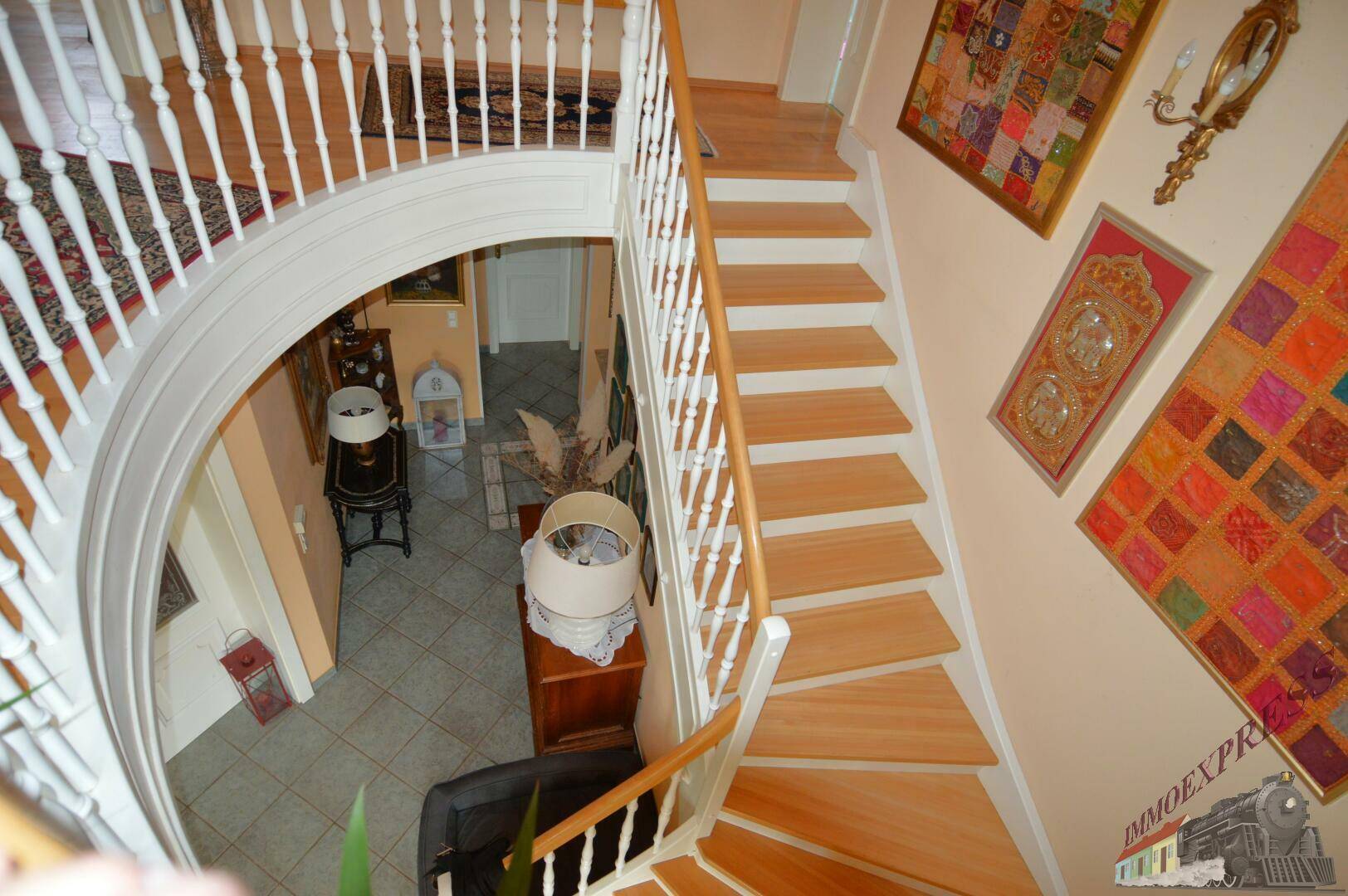 Blick von oben auf die geschwungene Holztreppe, die die Etagen des Hauses verbindet.