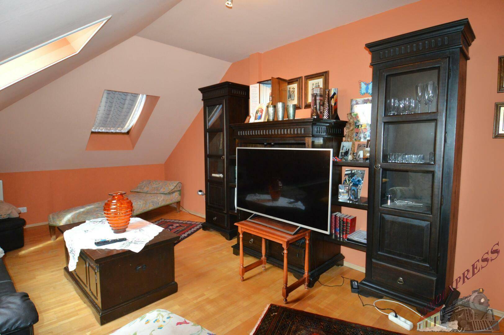 Wohnzimmer im Dachgeschoss mit TV-Möbeln, Sofa und Dachfenstern.