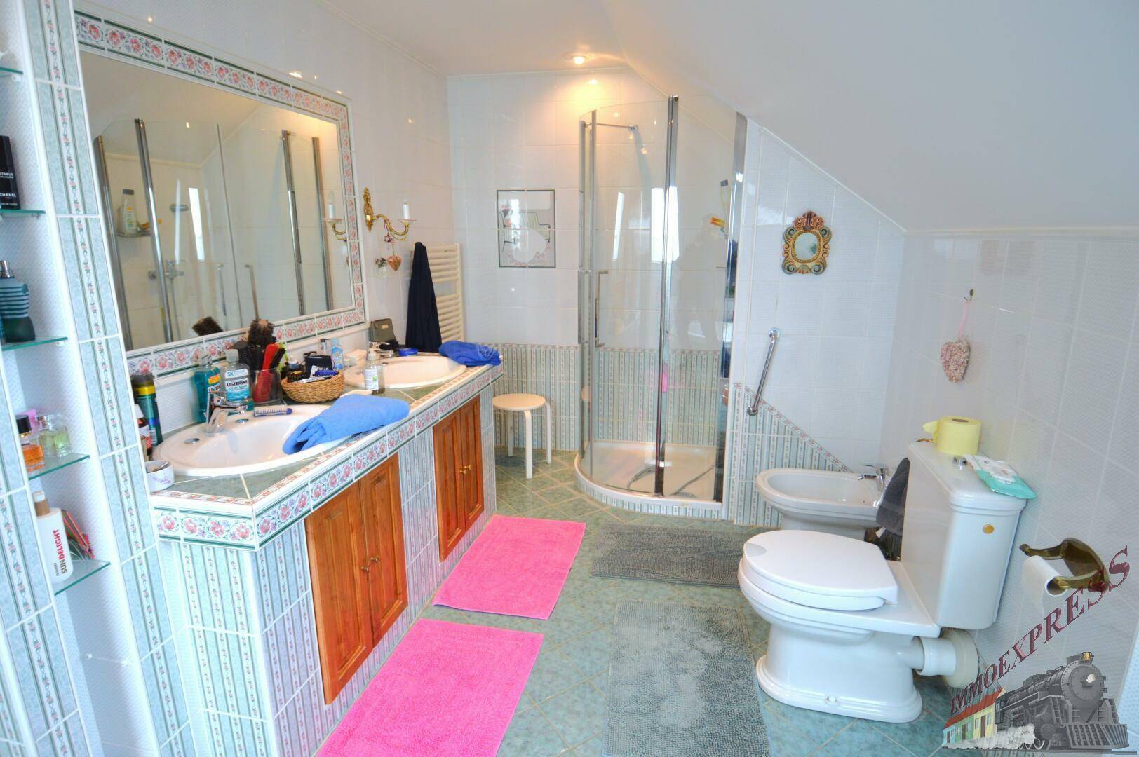 Badezimmer im Dachgeschoss mit Doppelwaschbecken, Duschkabine, Bidet und Dachschrägen.