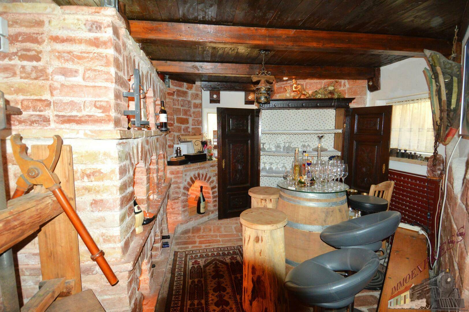 Weinkeller mit Ziegelwänden, Holzbalken und einer Bar aus Weinfässern.