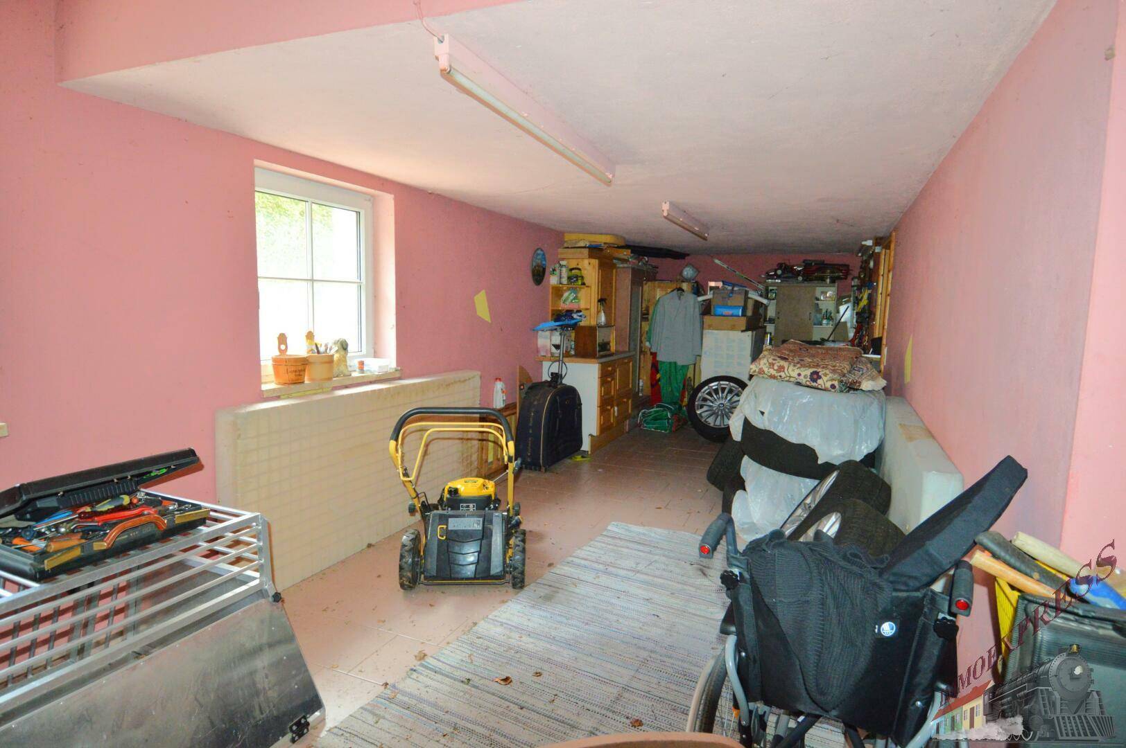 Geräumiger Kellerraum mit Fenster, rosa Wänden und verschiedenen Lagergegenständen.