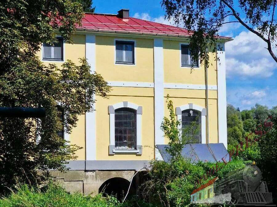 Die gelbe Fassade eines historischen Gebäudes mit roten Dächern und dekorativen Fenstern.