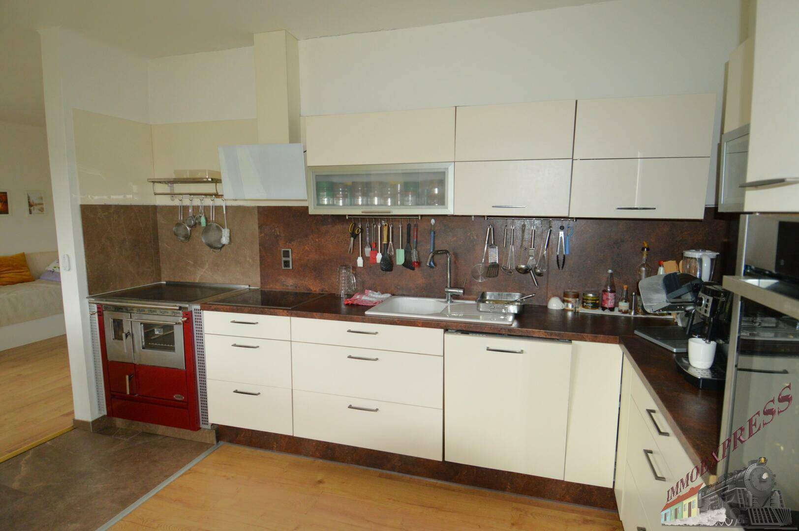 Moderne Einbauküche mit hellen Fronten, dunkler Arbeitsplatte und integriertem Holzherd.