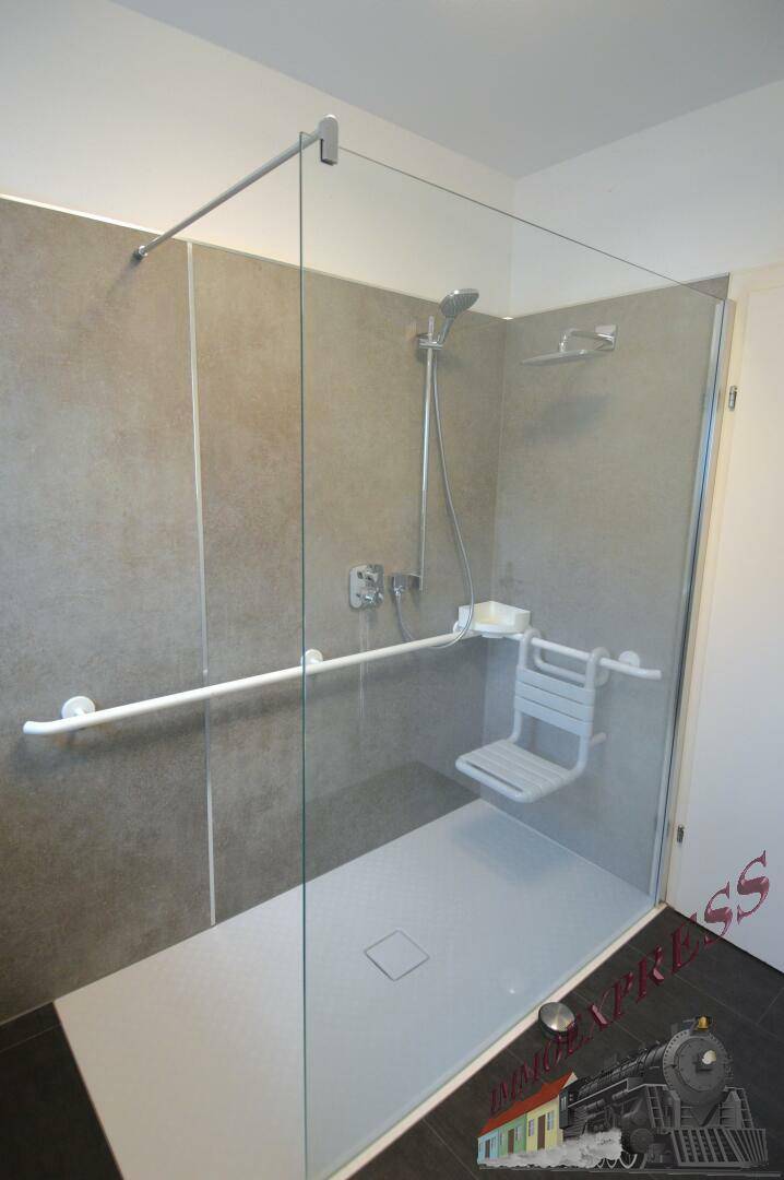 Barrierefreie Dusche mit Glasabtrennung, Haltegriffen und Duschsitz für Komfort.