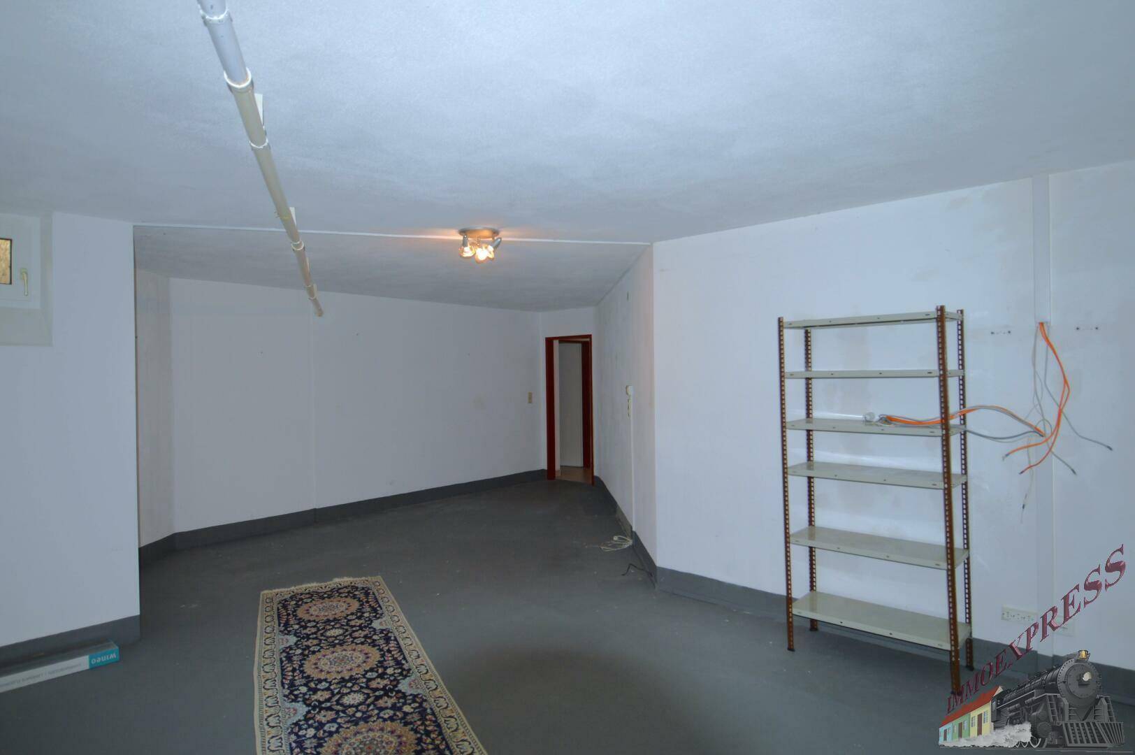 Geräumiger Kellerraum mit Teppichläufer, Regal und kleinem Fenster.