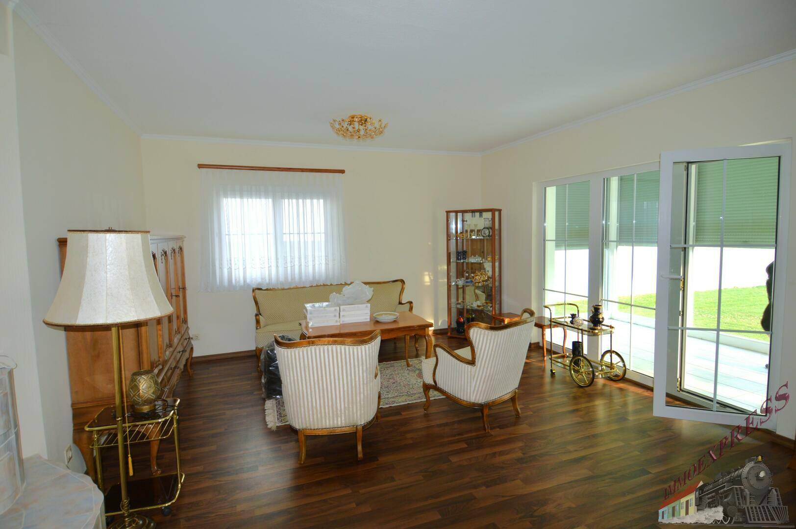 Geräumiges Wohnzimmer mit Holzboden, traditionellen Möbeln und großen Fenstern zum Garten.