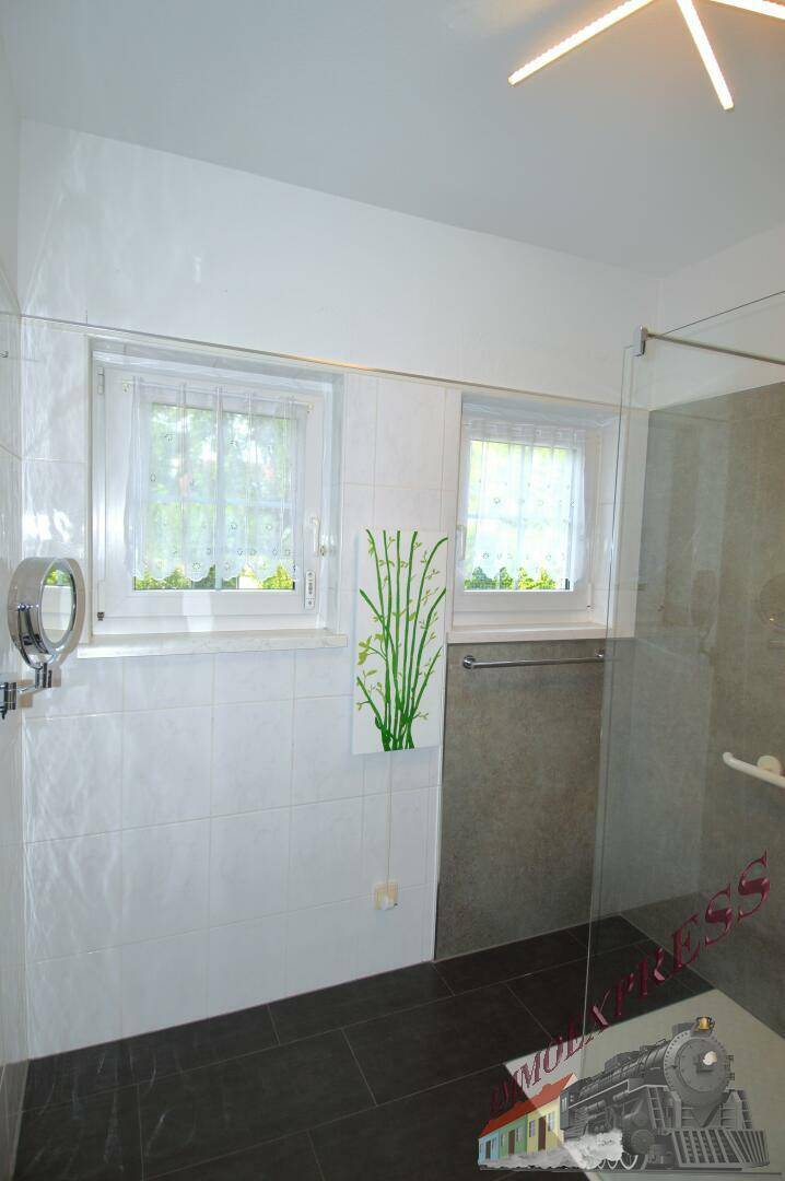 Modernes Badezimmer mit zwei Fenstern, dunklen Fliesen und einer begehbaren Dusche.