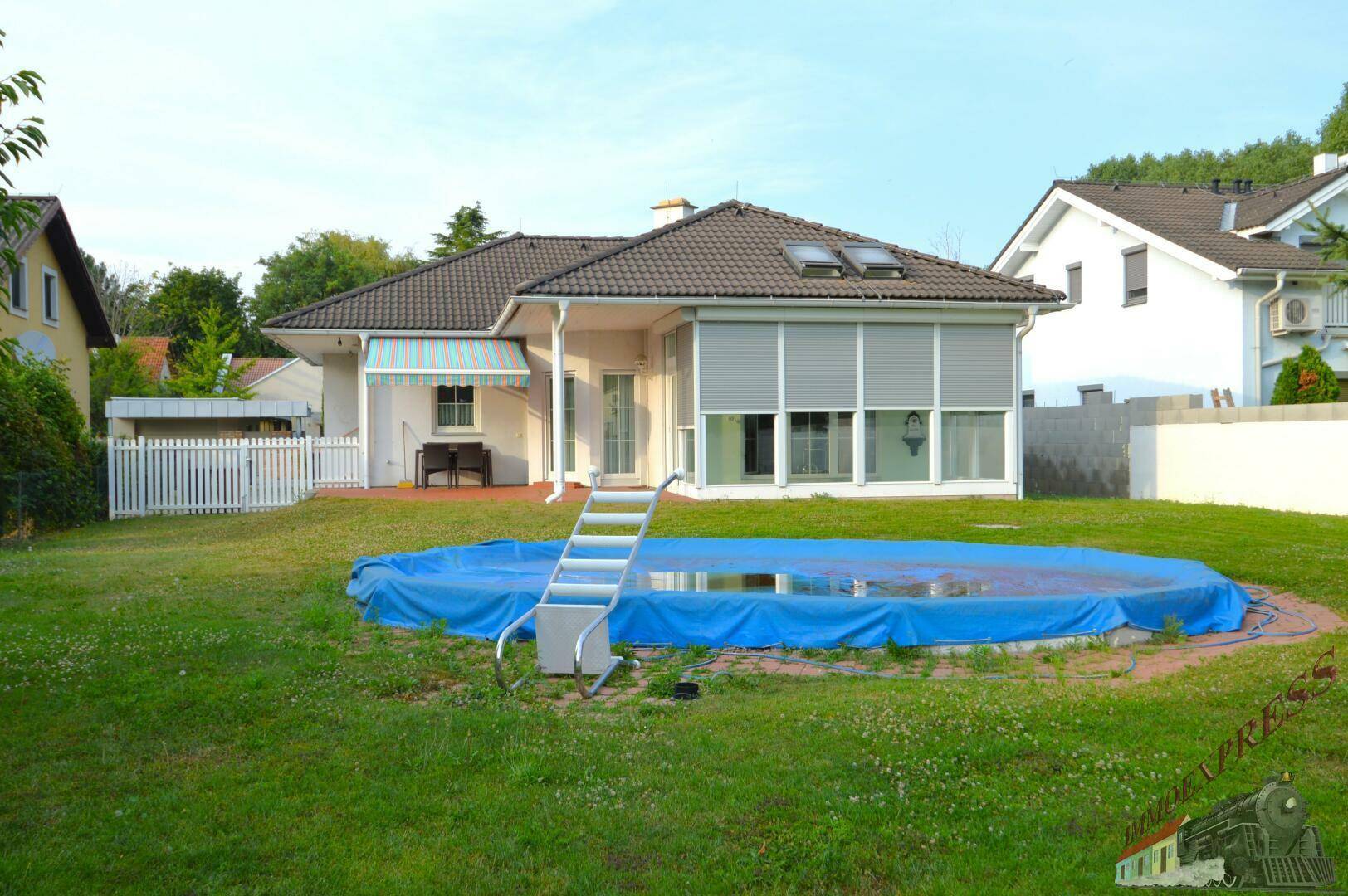 Außenansicht des Hauses mit großem Garten und abgedecktem Aufstellpool.