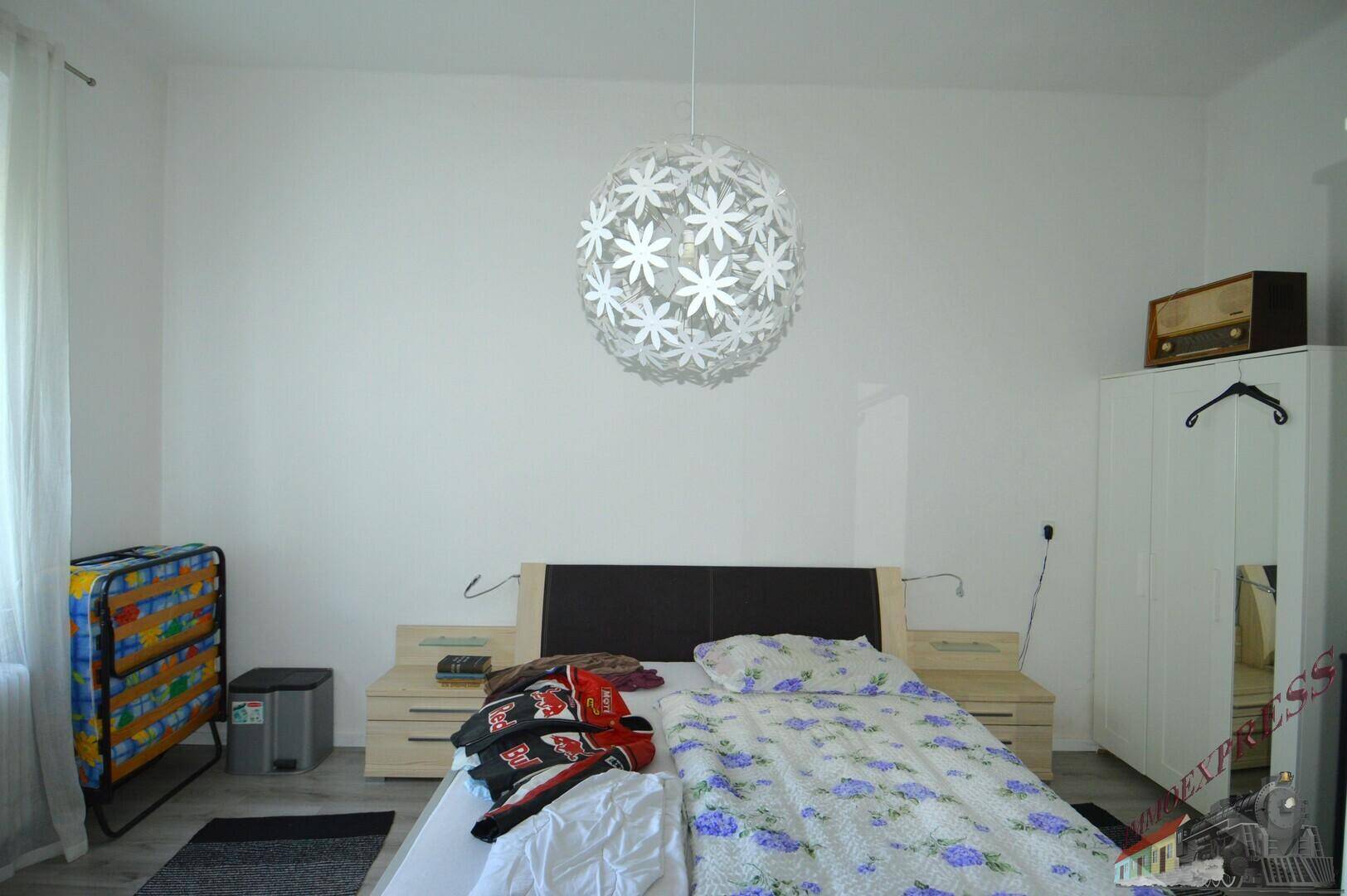 Helles Schlafzimmer mit Doppelbett, Nachttischen und einem großen Kleiderschrank.