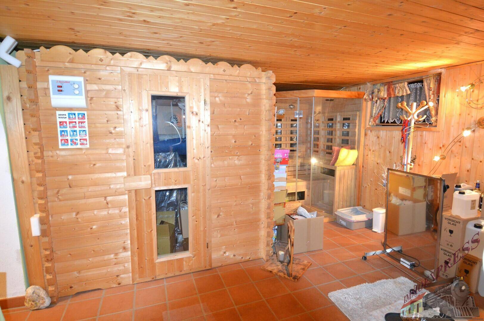 Geräumiger Kellerraum mit Holzsauna und Infrarotkabine, ideal für Wellness und Entspannung.