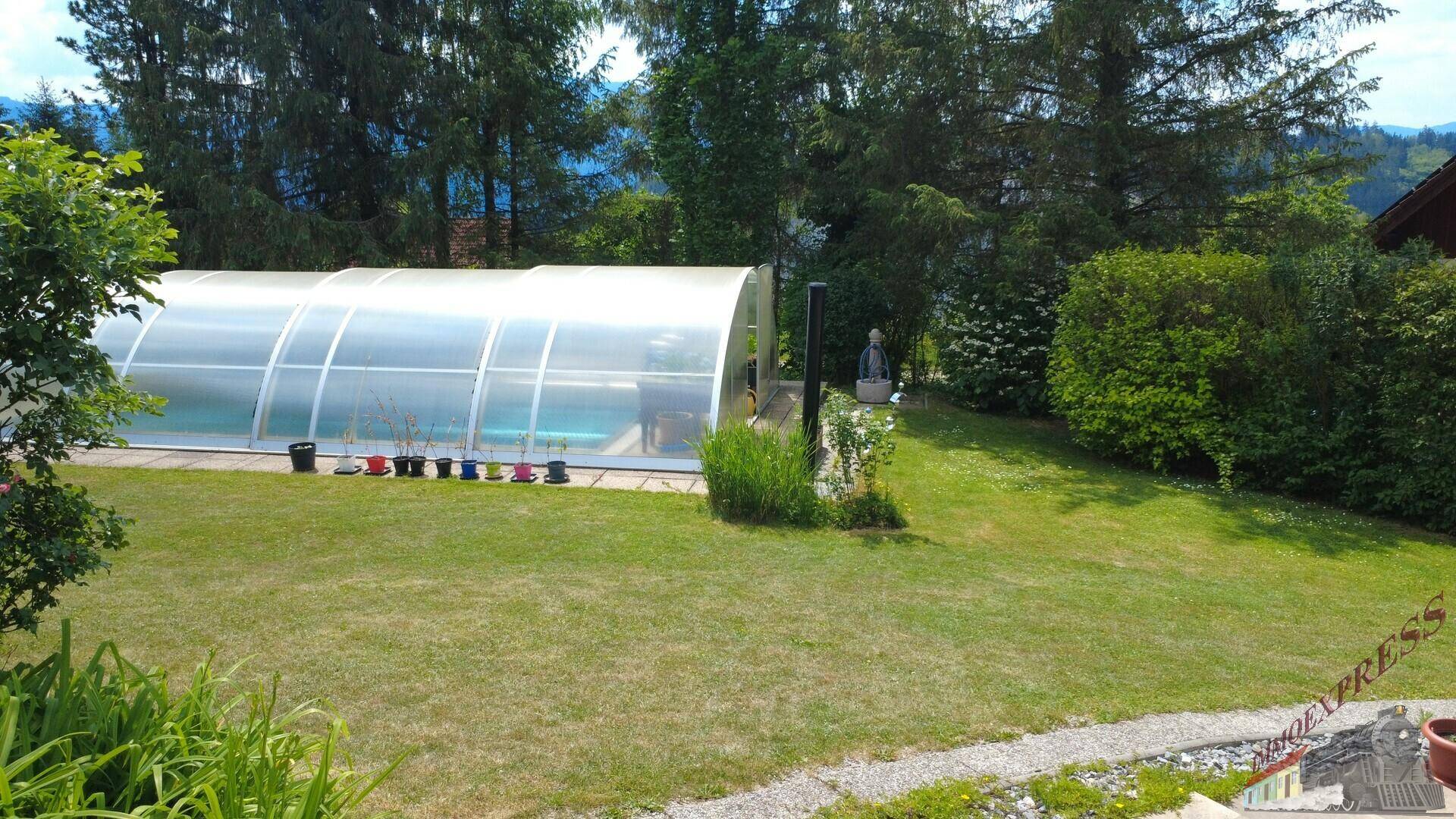 Großer Gartenbereich mit überdachtem Swimmingpool und weitläufiger Rasenfläche.