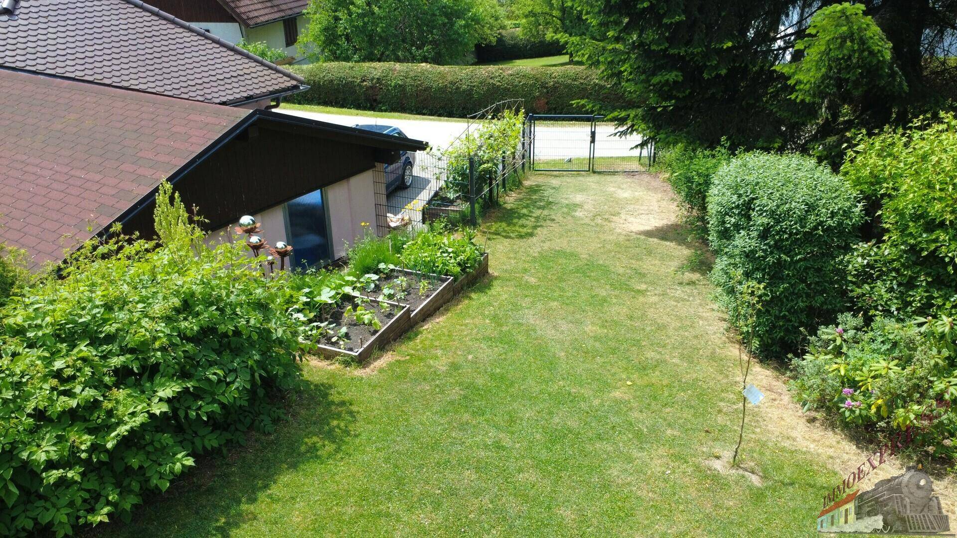 Gartenbereich mit Hochbeet für Gemüseanbau und einem Zugangstor.