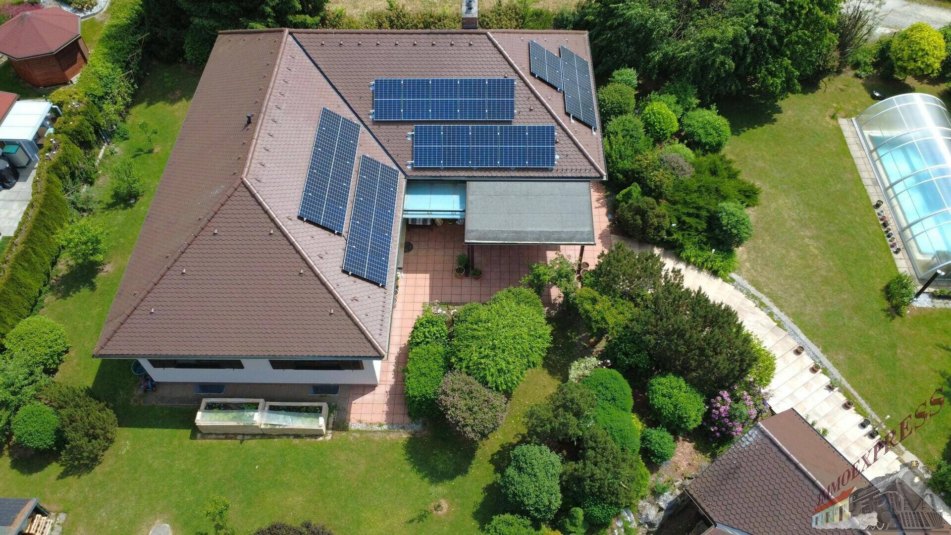 Weitläufige Luftaufnahme des Anwesens mit Haus, Garten, Solaranlagen und überdachtem Pool.