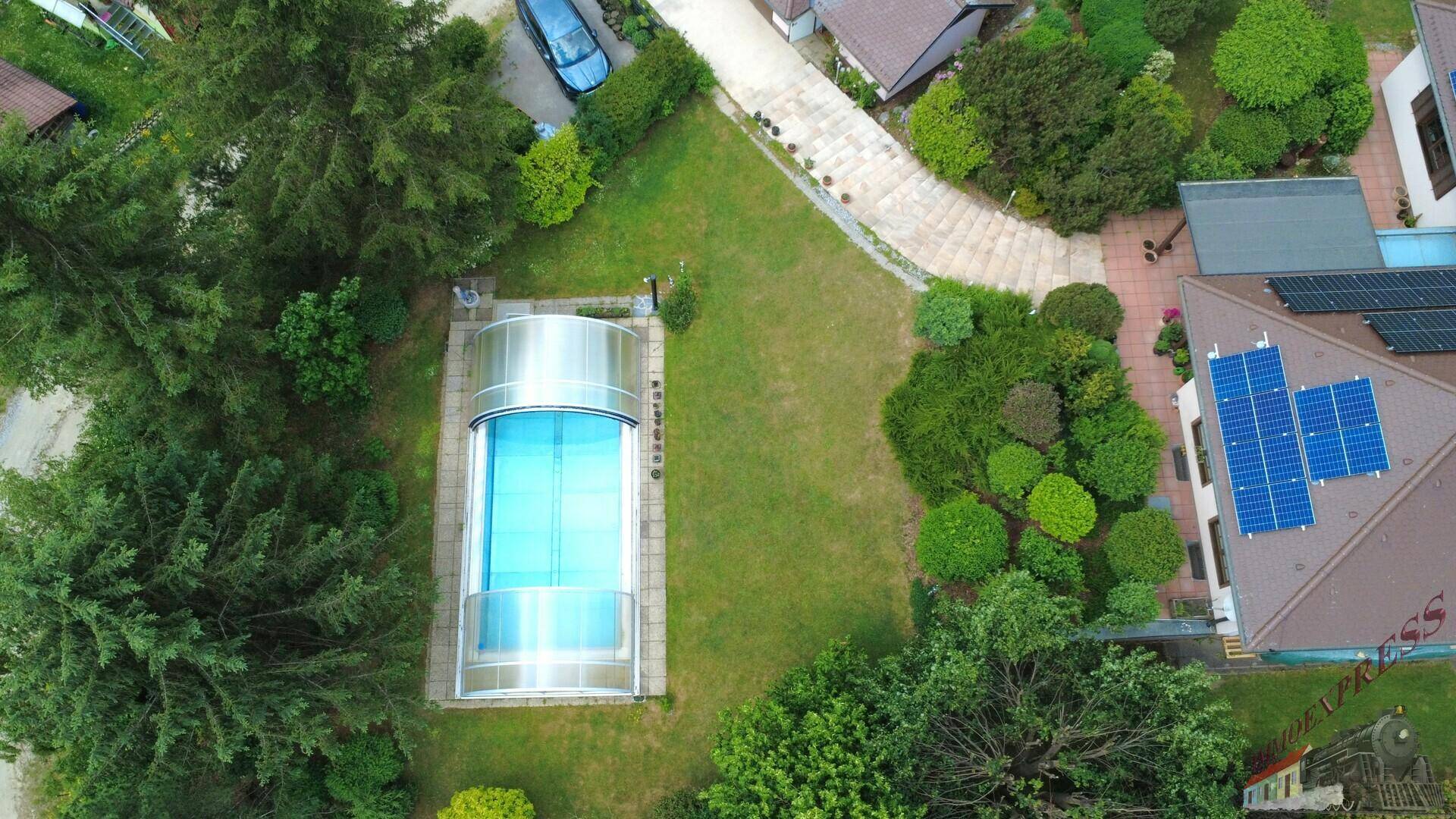 Überblick über das Anwesen mit großem Garten, überdachtem Pool und Solaranlagen auf dem Hausdach.
