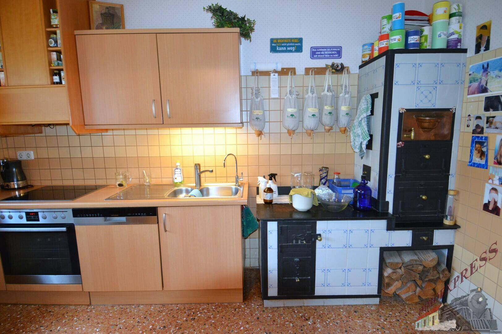 Küche mit traditionellem Kachelofen, modernen Einbauschränken und Terrazzoboden.