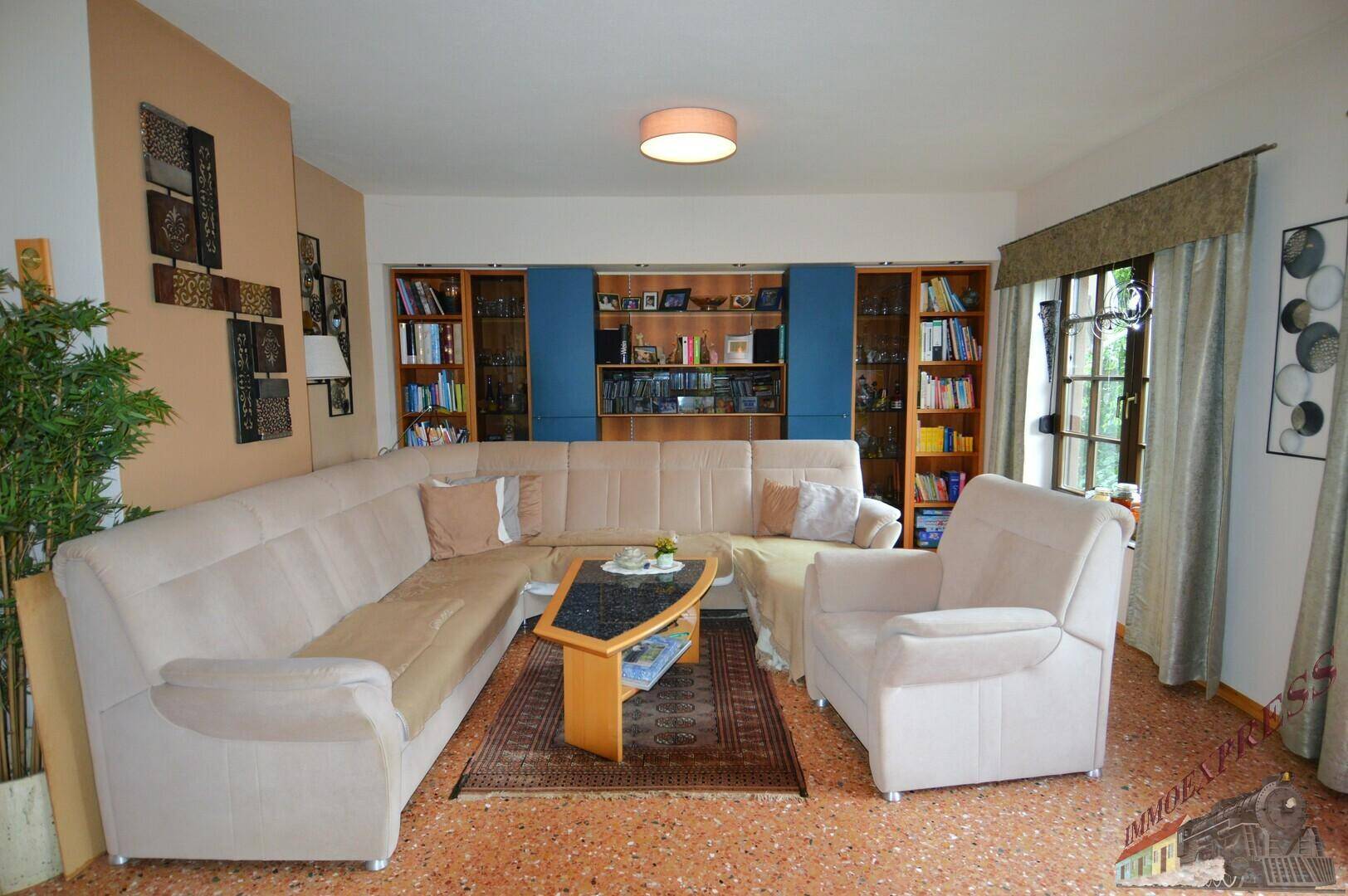 Geräumiges Wohnzimmer mit bequemer Sitzecke, Terrazzoboden und eingebauten Regalen.