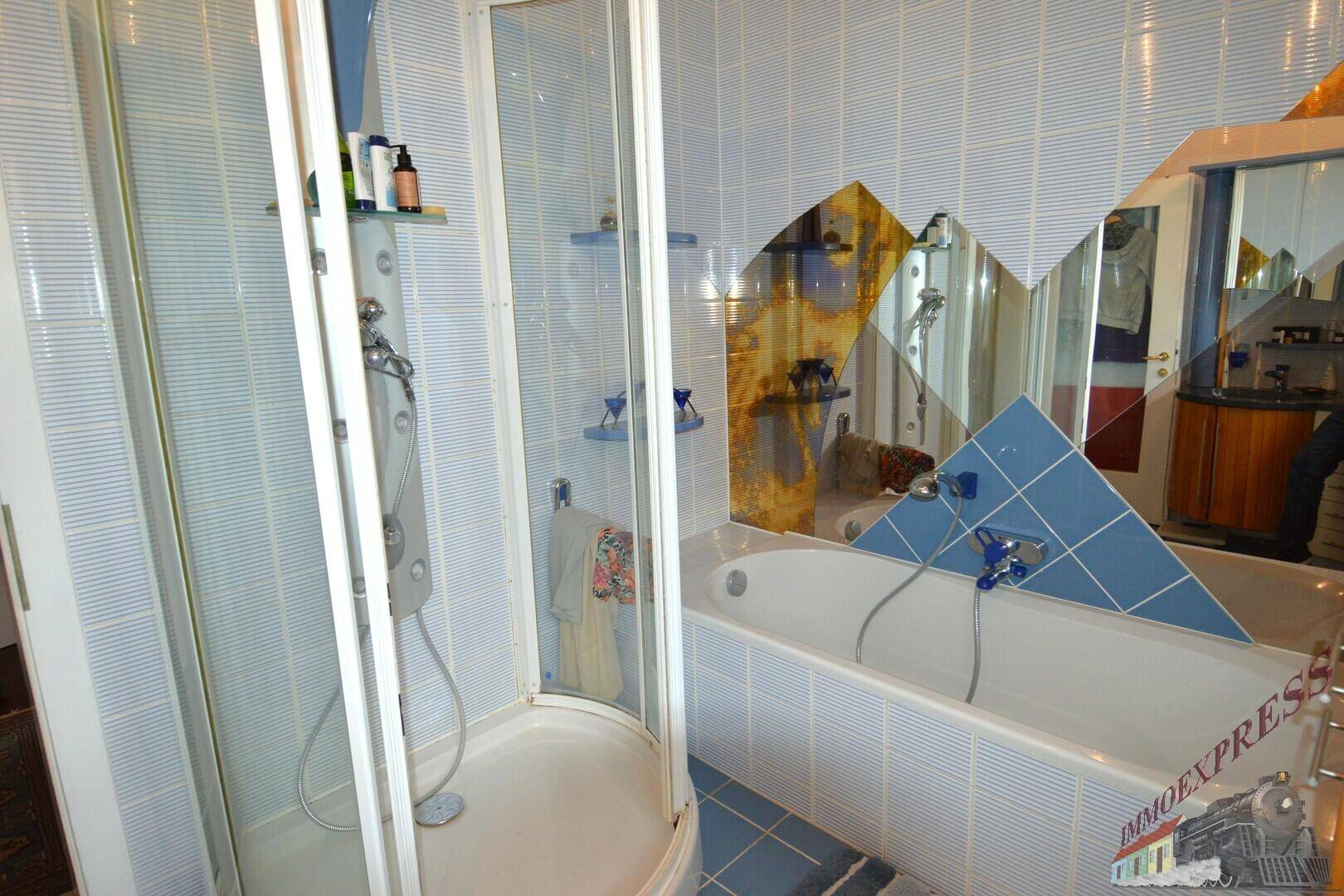 Badezimmer mit Duschkabine und Badewanne, dekoriert mit blauen und weißen Fliesen.