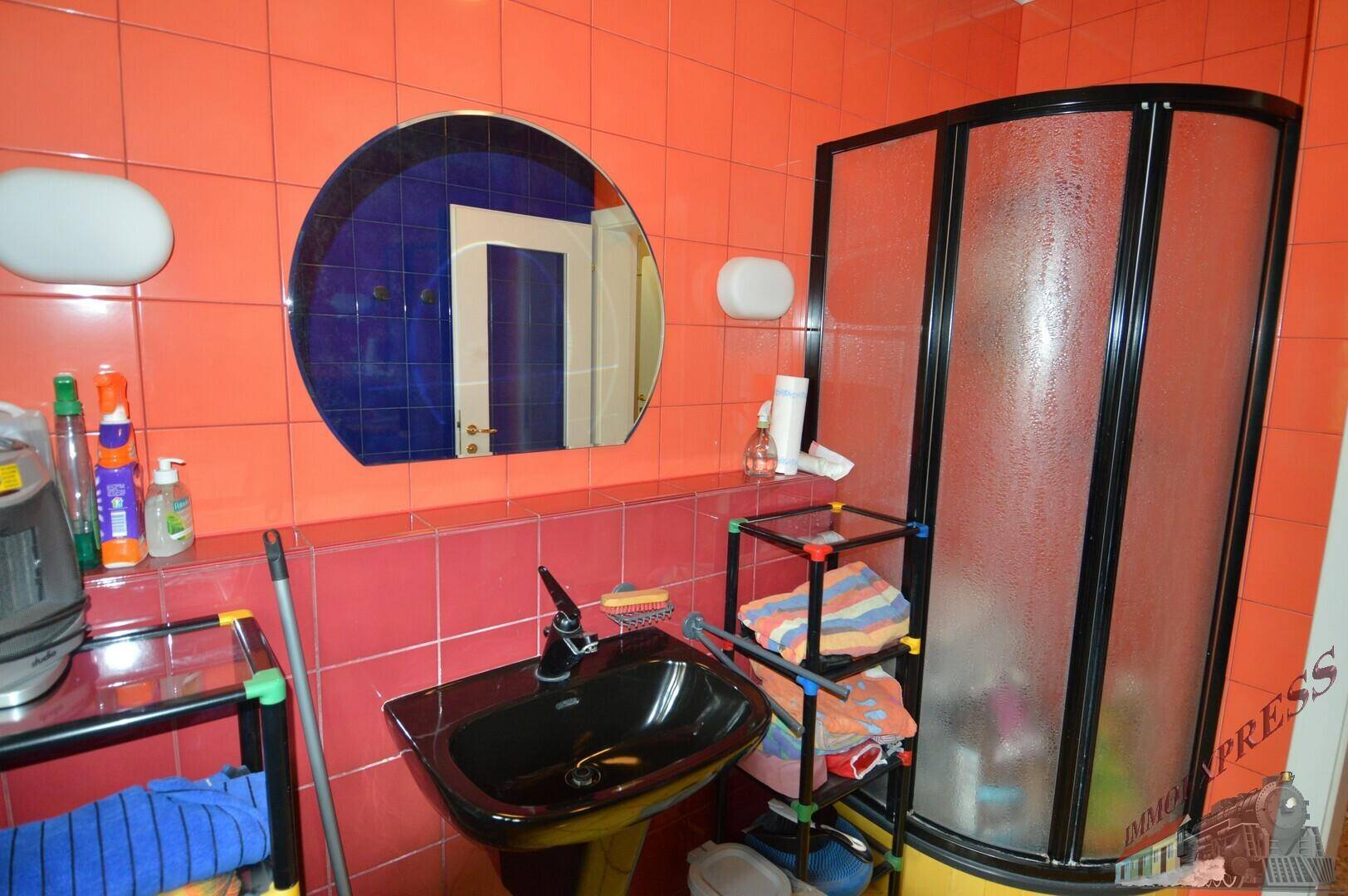Badezimmer mit farbenfrohen Fliesen, schwarzem Waschbecken und Duschkabine.