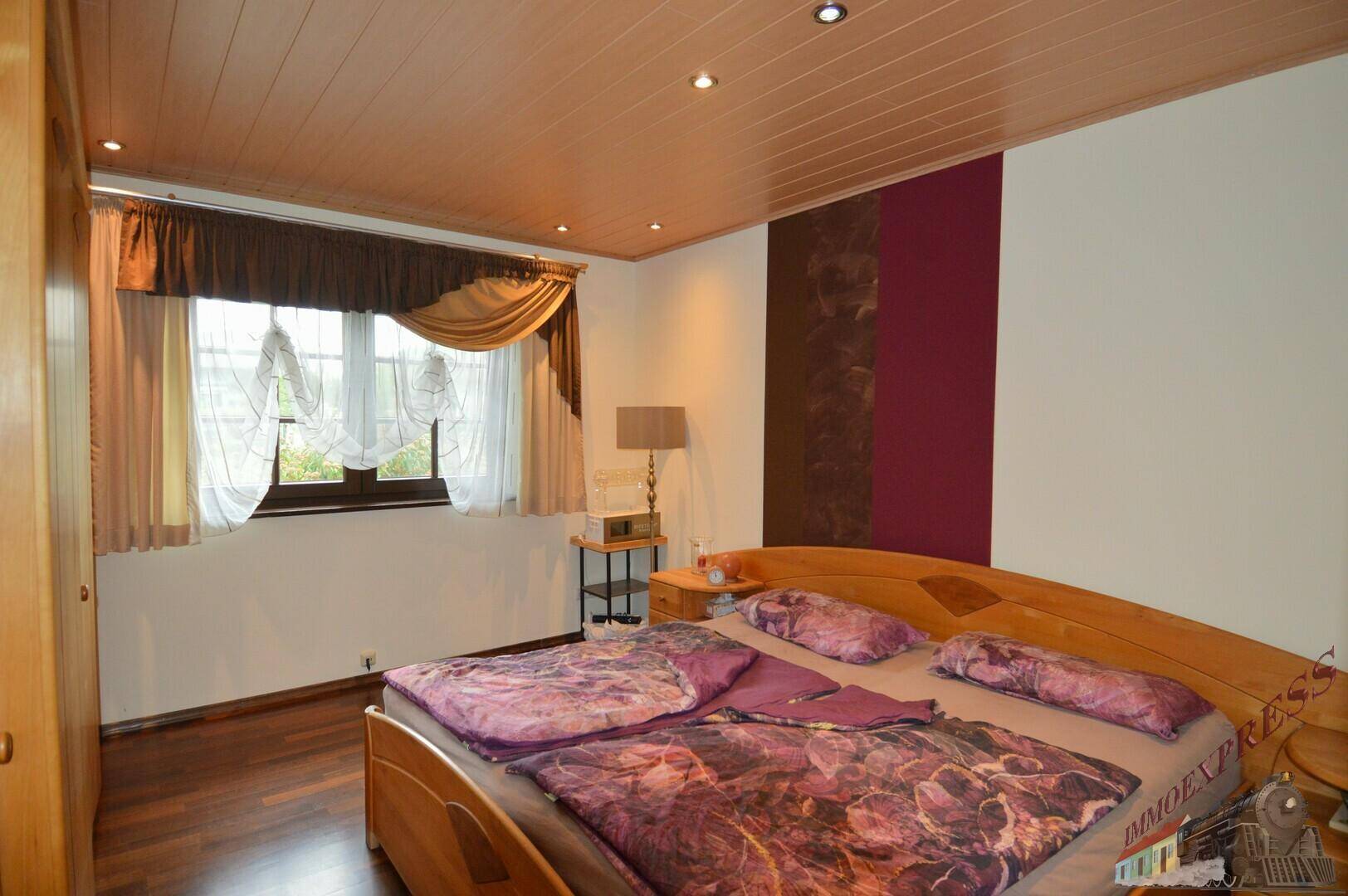 Gemütliches Schlafzimmer mit Doppelbett, Holzboden und dekorativer Wandgestaltung.