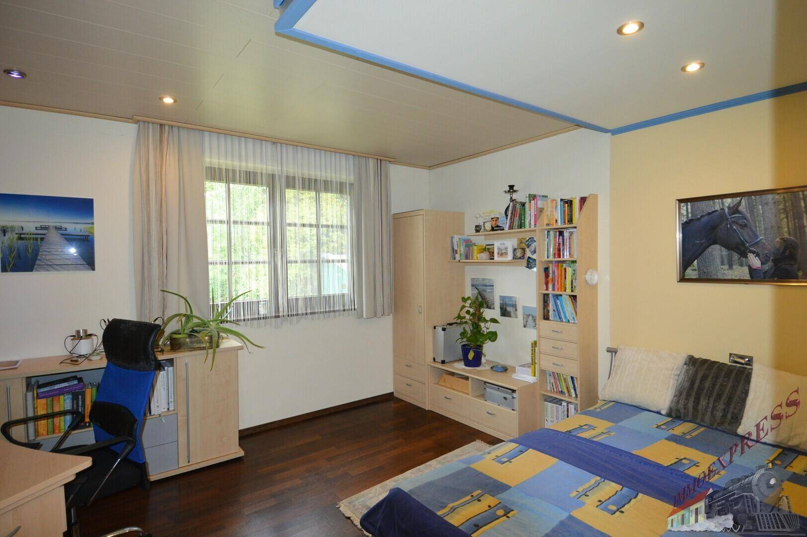 Schlafzimmer mit Holzboden, Einzelbett und Bücherregal, ideal als Gäste- oder Kinderzimmer.