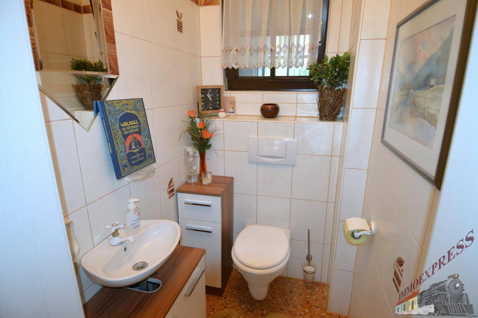 Kleines Gäste-WC mit Wand-WC, Waschbecken und Fenster für natürliche Belüftung.