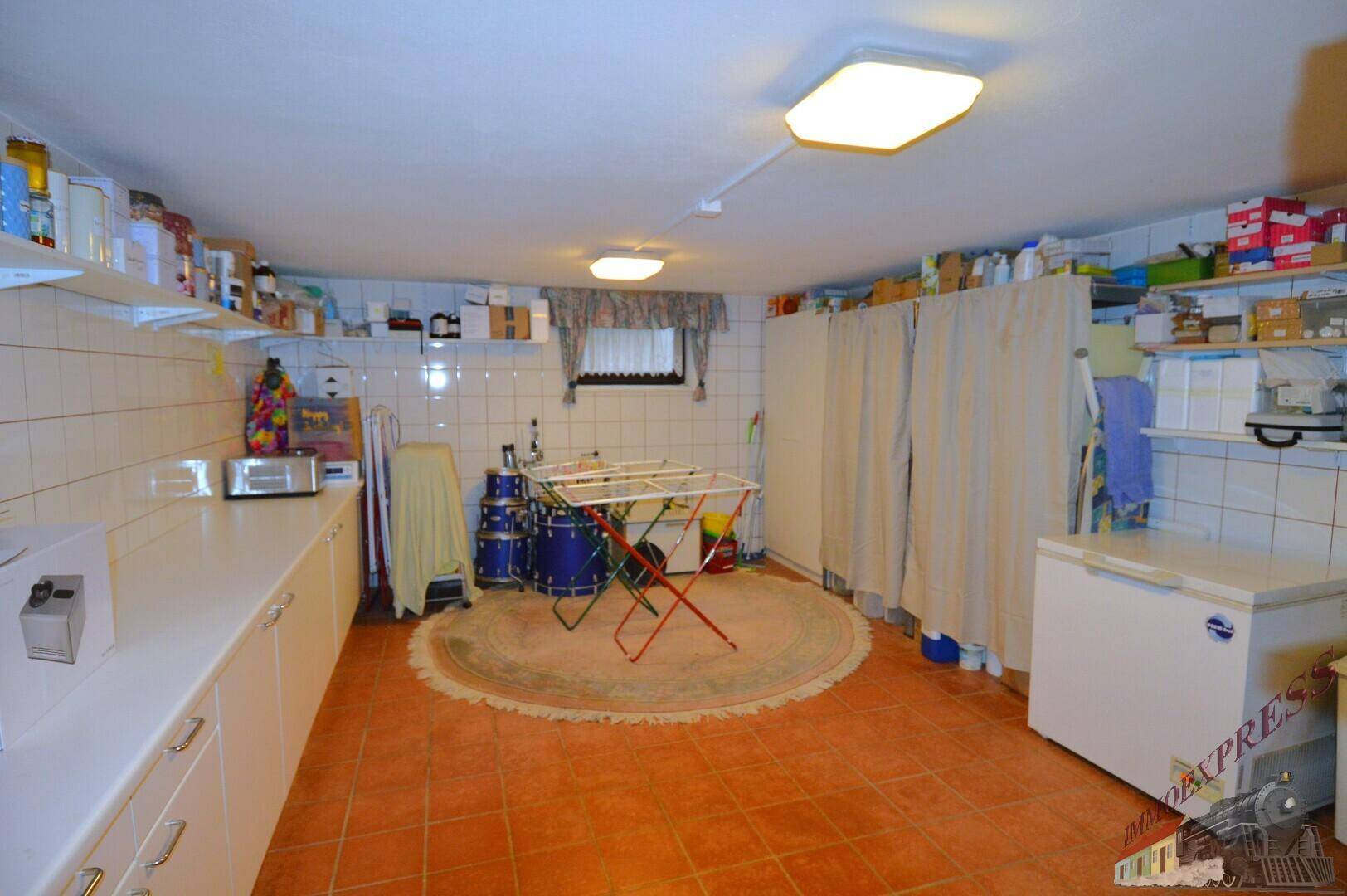 Waschküche im Keller mit Waschbecken, Regalen und Gefriertruhe, praktisch für den Haushalt.