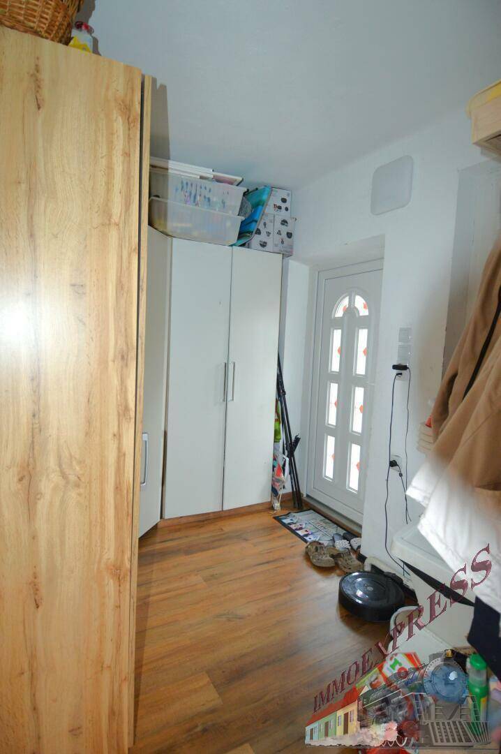 Eingangsbereich mit Holzboden, Garderobenschrank und einer weißen Eingangstür.