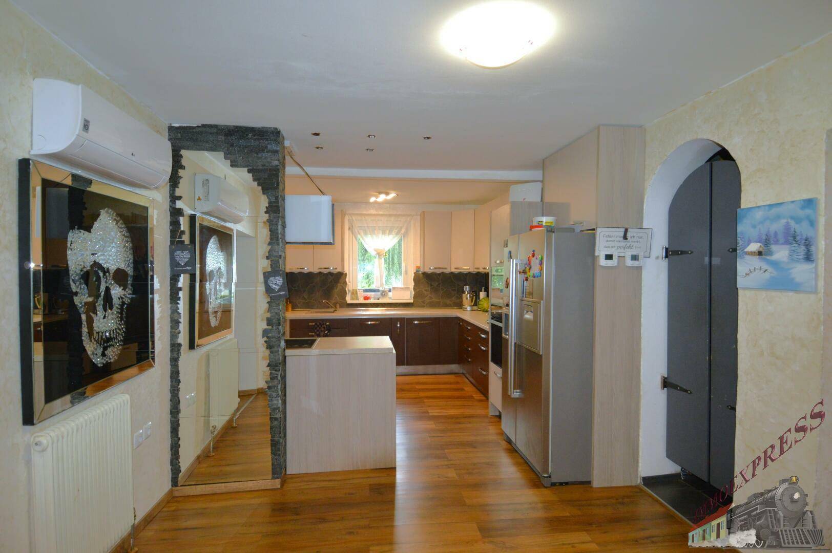 Offene Küche mit Holzboden, modernen Geräten und einem Durchgang zum Wohnbereich.