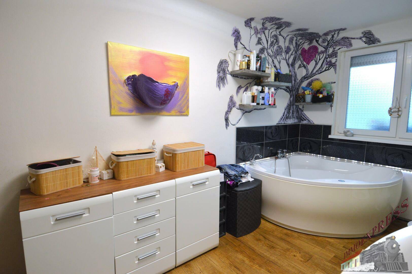 Badezimmer mit Eckbadewanne, Fenster und einem Sideboard für zusätzlichen Stauraum.