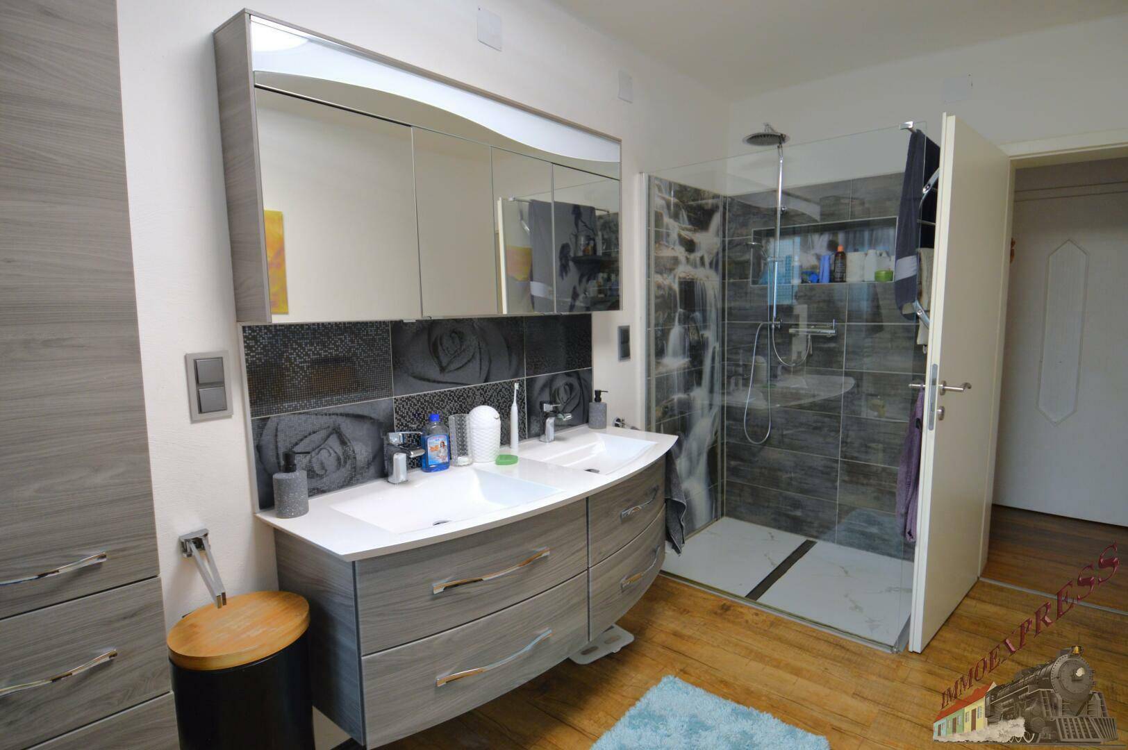 Modernes Badezimmer mit Doppelwaschbecken, Spiegelschrank und begehbarer Dusche.