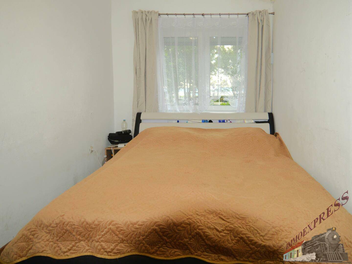 Schlafzimmer mit Doppelbett, Holzboden und einem Fenster mit Blick ins Grüne.