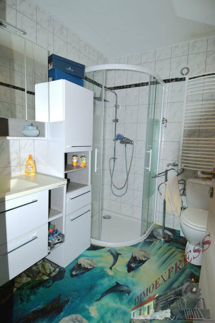 Badezimmer mit Duschkabine, Toilette und einem auffälligen Bodenbelag.