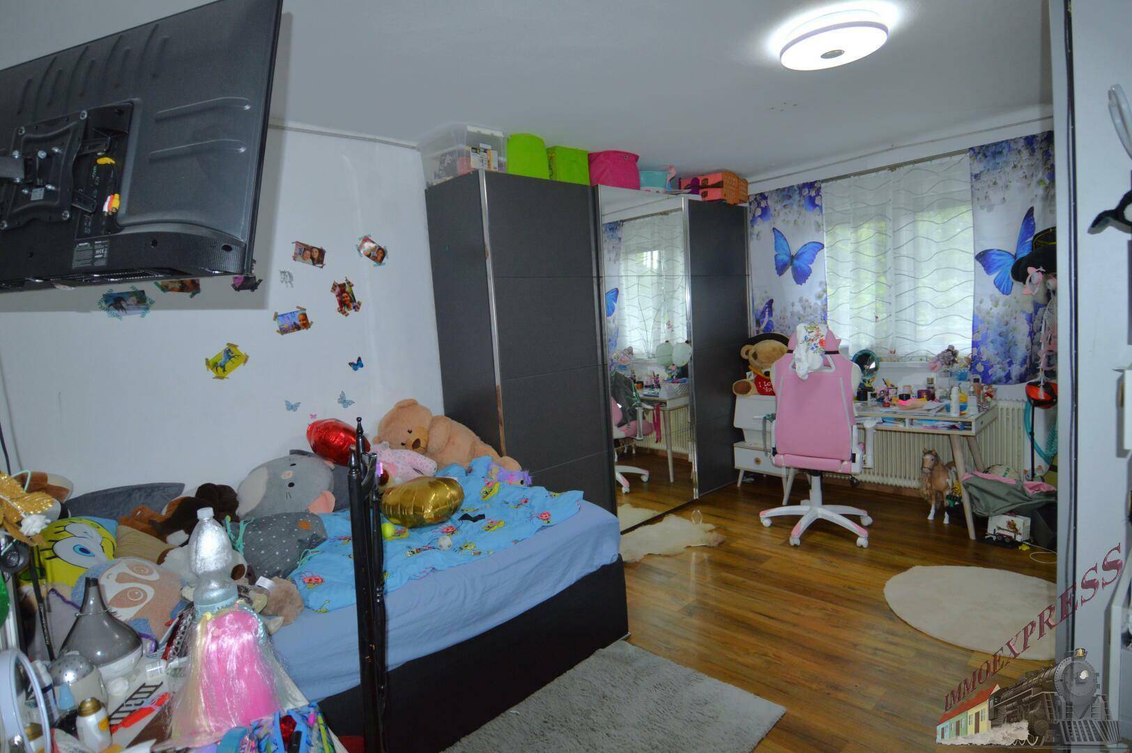 Kinderzimmer mit Holzboden, großem Bett, Schränken und verspielter Dekoration.