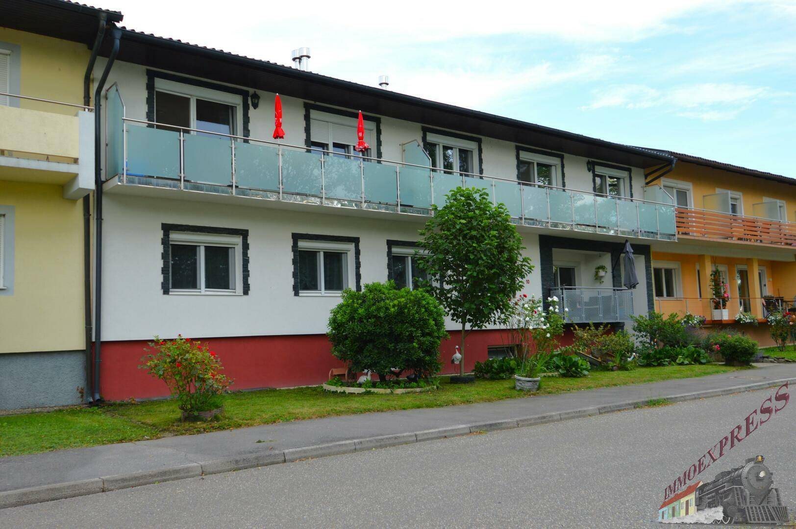 Mehrfamilienhaus mit Balkonen und gepflegter Vorgartenanlage an einer ruhigen Straße.