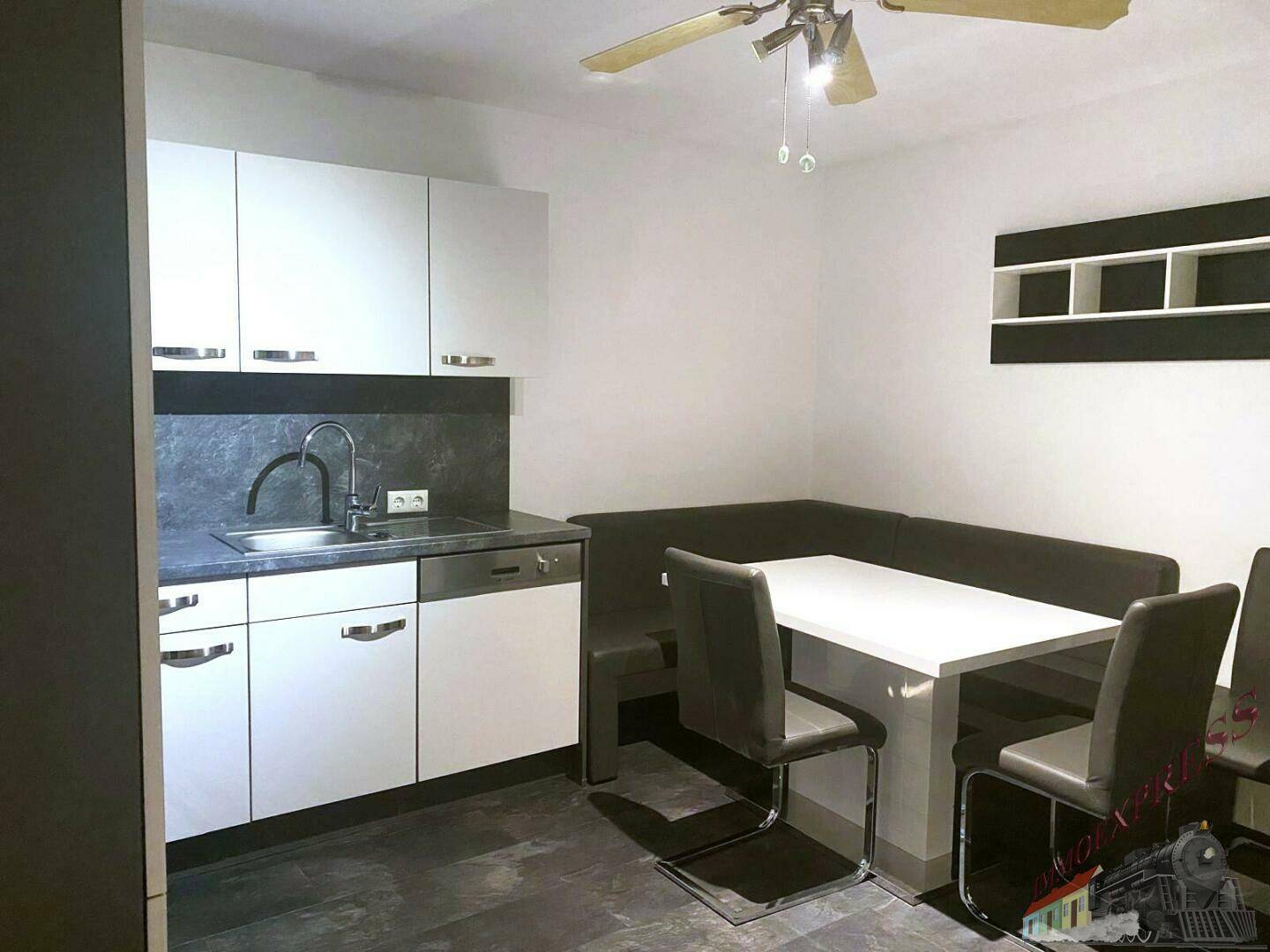 Funktionale Küchenzeile mit Essbereich, weißen Schränken und Deckenventilator.