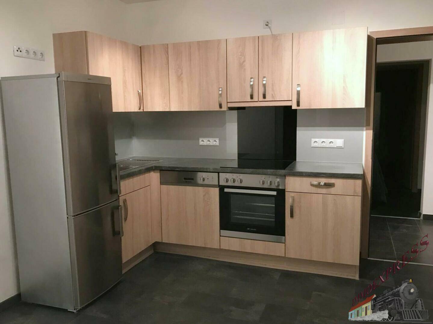 Funktionale Küche mit hellen Holzfronten, dunkler Arbeitsplatte und modernen Einbaugeräten.