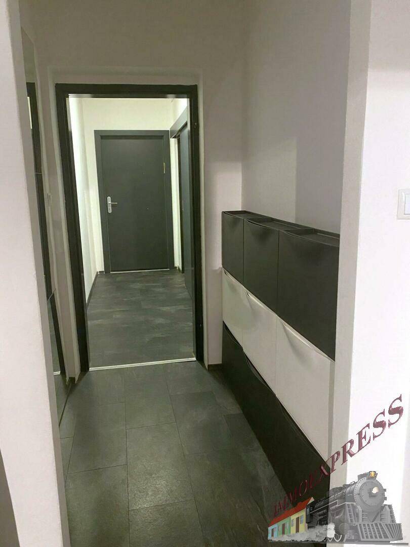Heller Flur mit dunklem Fliesenboden und praktischem Schuhschrank.