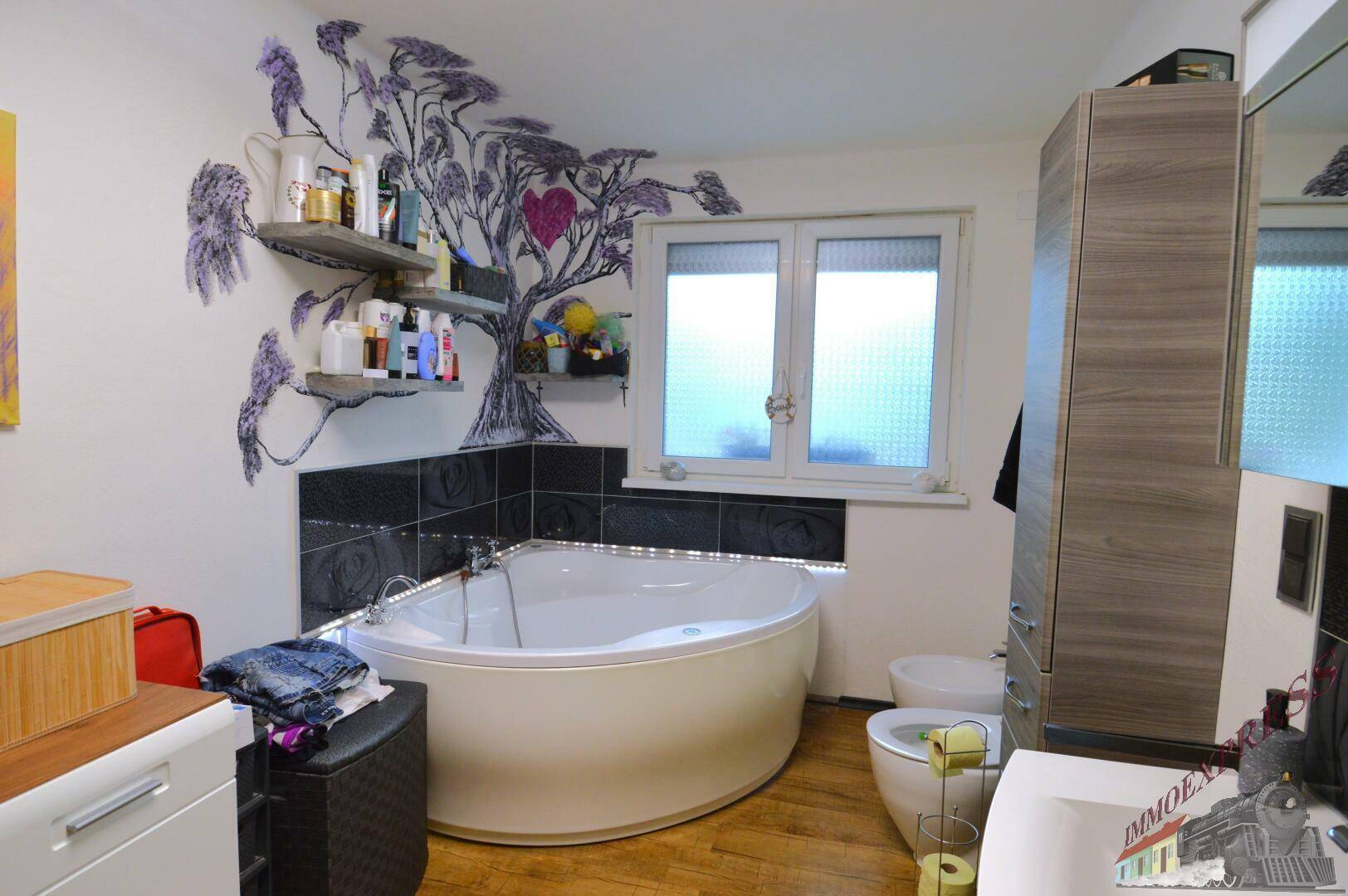 Geräumiges Badezimmer mit Eckbadewanne, Fenster und kreativer Wandgestaltung.