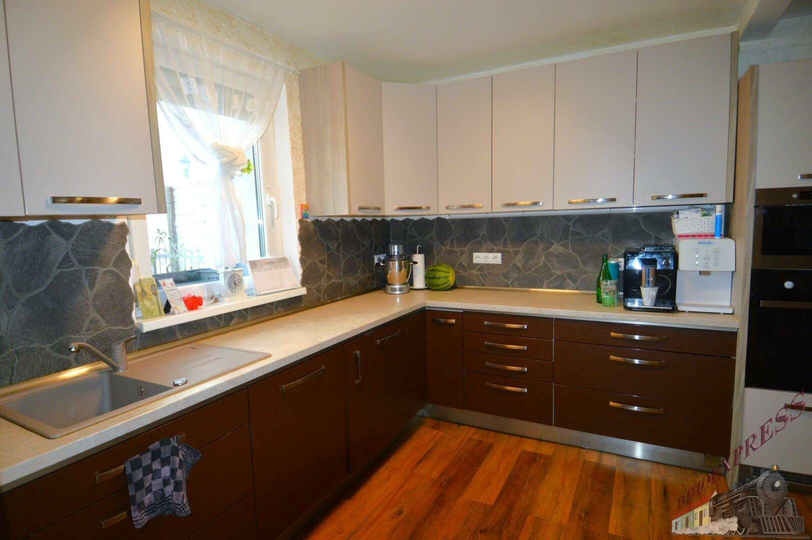 Moderne Küche mit hellen Ober- und dunklen Unterschränken, Spüle und Fenster.