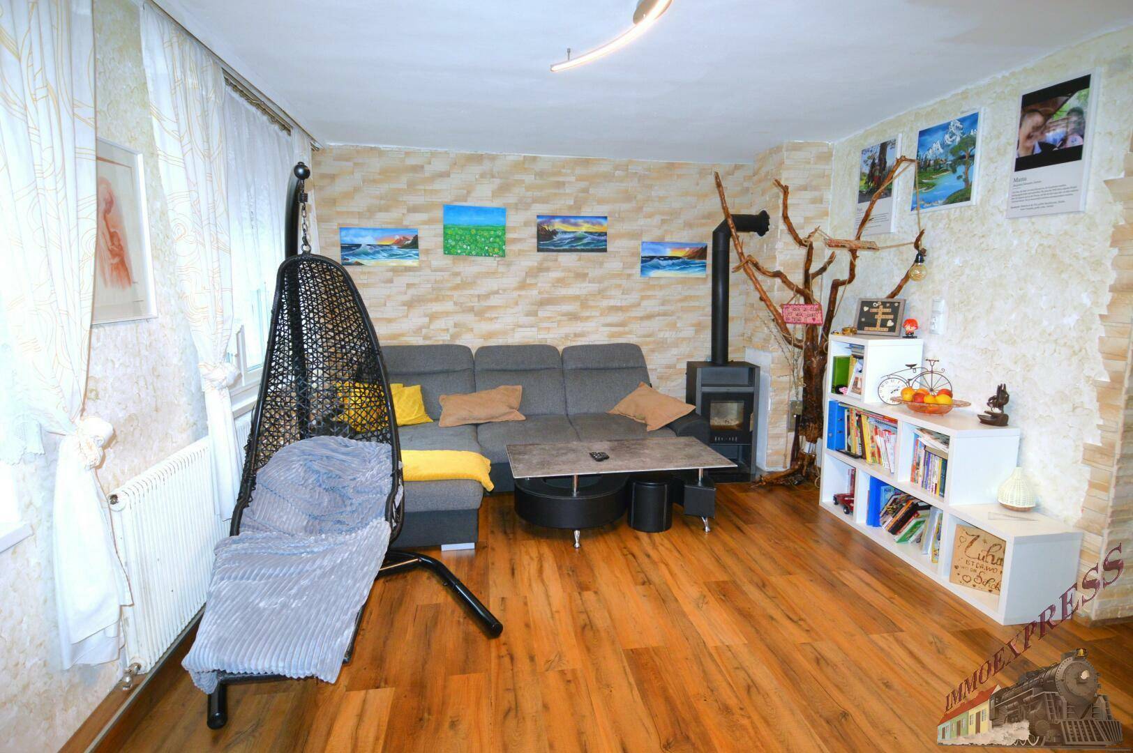 Wohnzimmer mit Holzboden, Kaminofen und einer Steinwand, die eine warme Atmosphäre schafft.