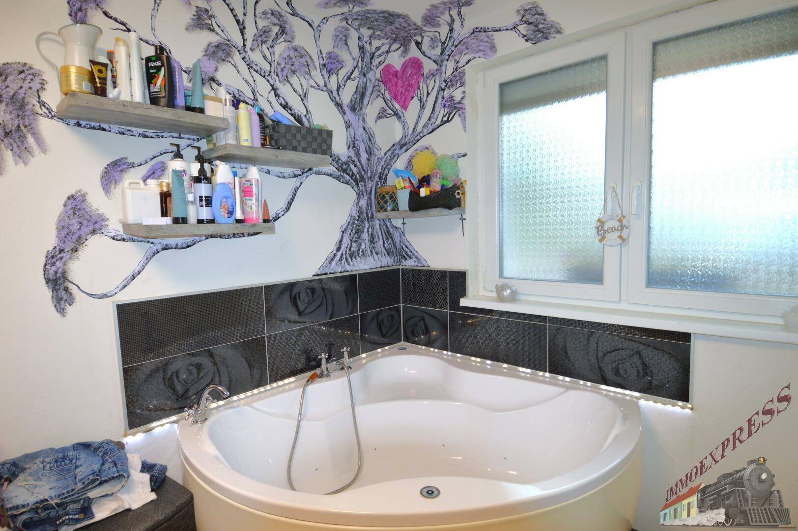 Eckbadewanne mit LED-Beleuchtung in einem Badezimmer mit Fenster und dekorativer Wandmalerei.