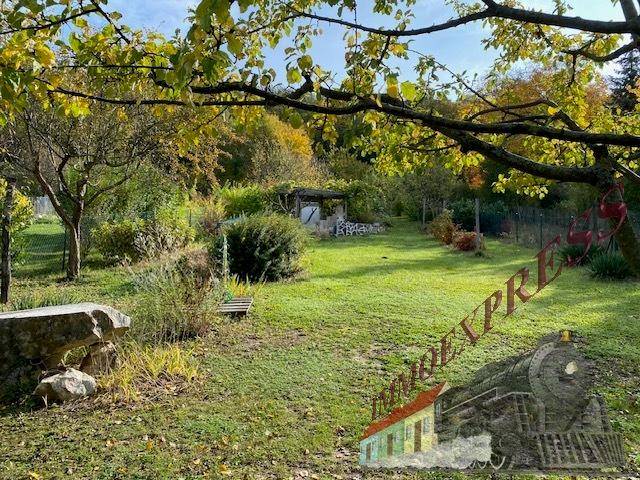 Herbstlicher Garten mit bunten Bäumen, Rasenflächen und natürlichen Felsen in der Landschaft.