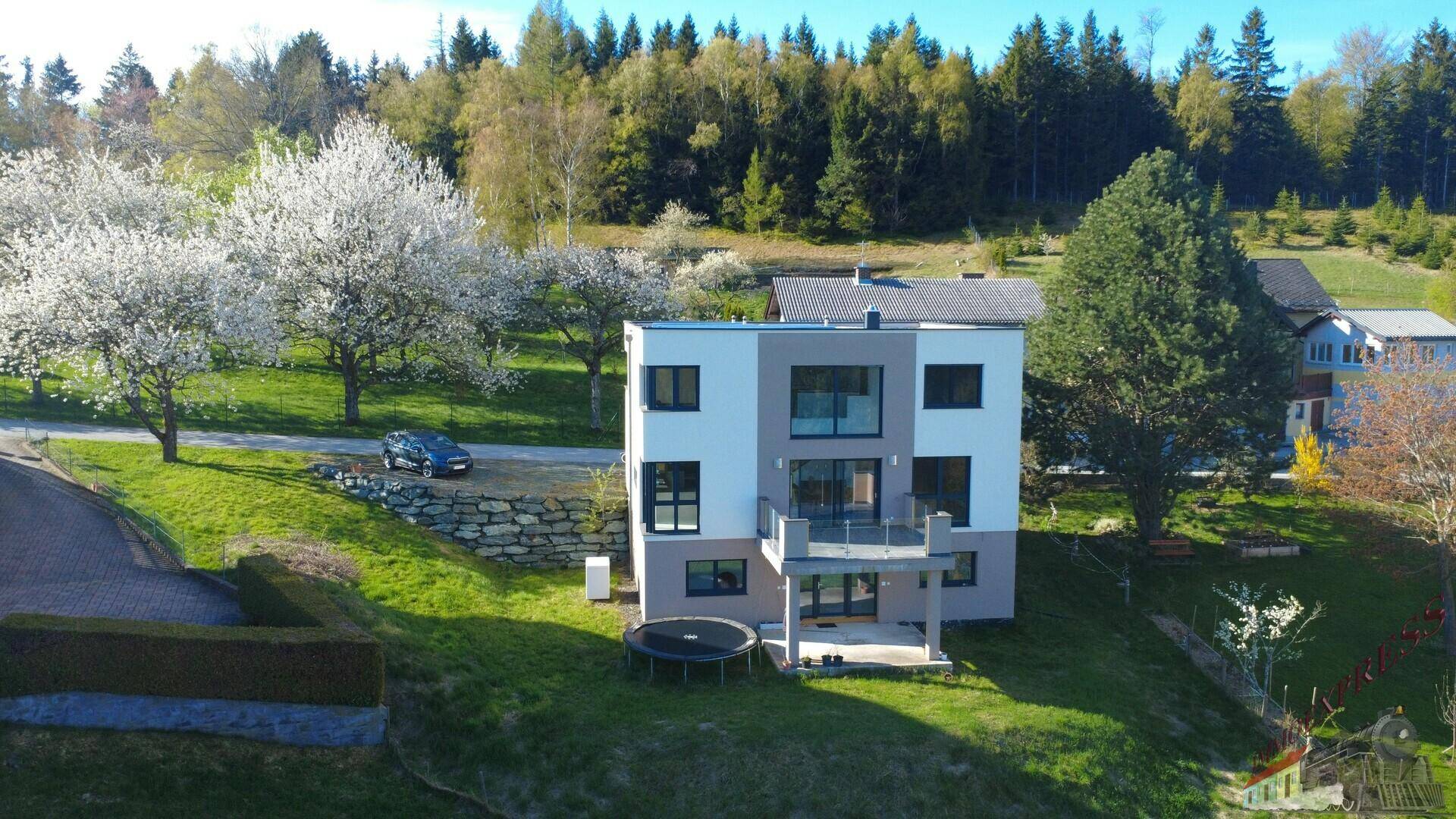 Modernes Einfamilienhaus in ländlicher Umgebung mit Terrasse und Trampolin.