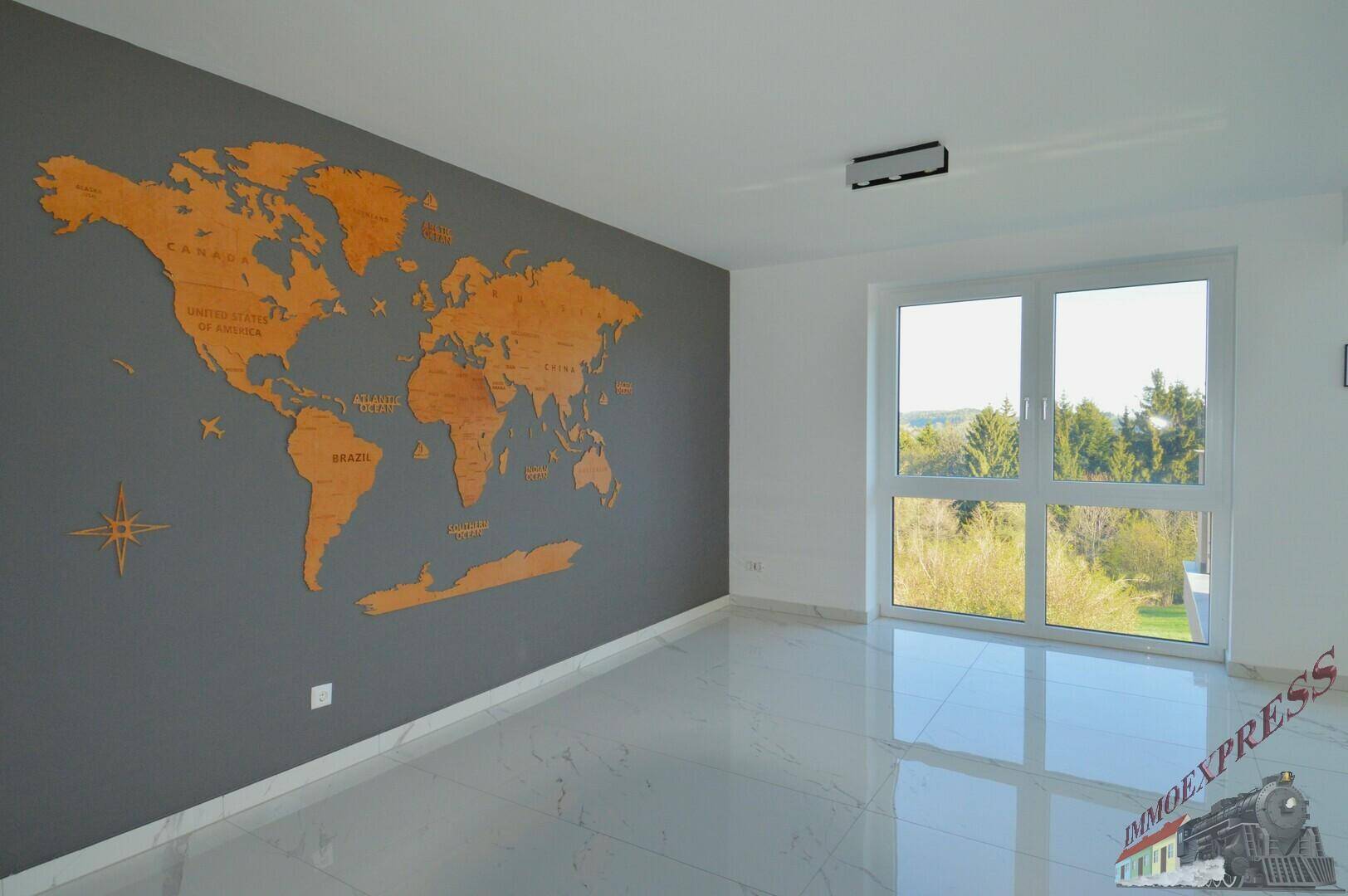 Wohnzimmer mit großer Weltkarte an der Wand und weitem Ausblick durch das Fenster in die Natur.