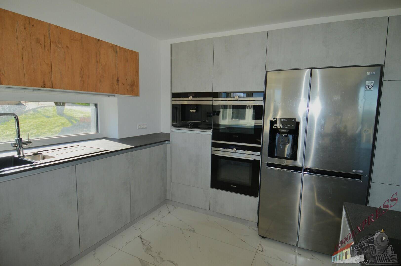 Hochwertige Einbauküche mit modernen grauen Fronten, integrierten Backöfen und großem Kühlschrank.