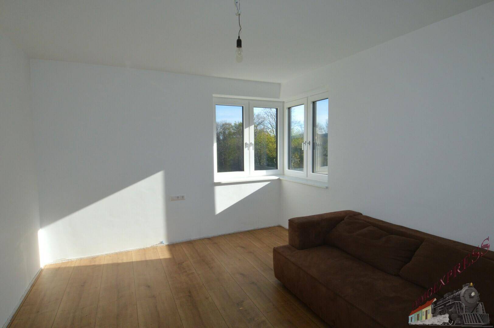 Lichtdurchflutetes Wohnzimmer mit Holzboden und Eckfenstern, die einen schönen Ausblick bieten.
