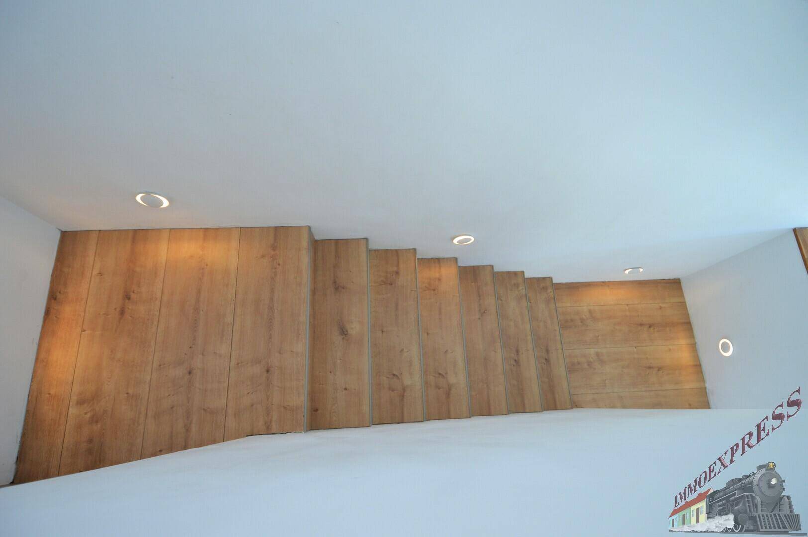 Moderne Holztreppe mit indirekter Beleuchtung, die die verschiedenen Ebenen des Hauses verbindet.
