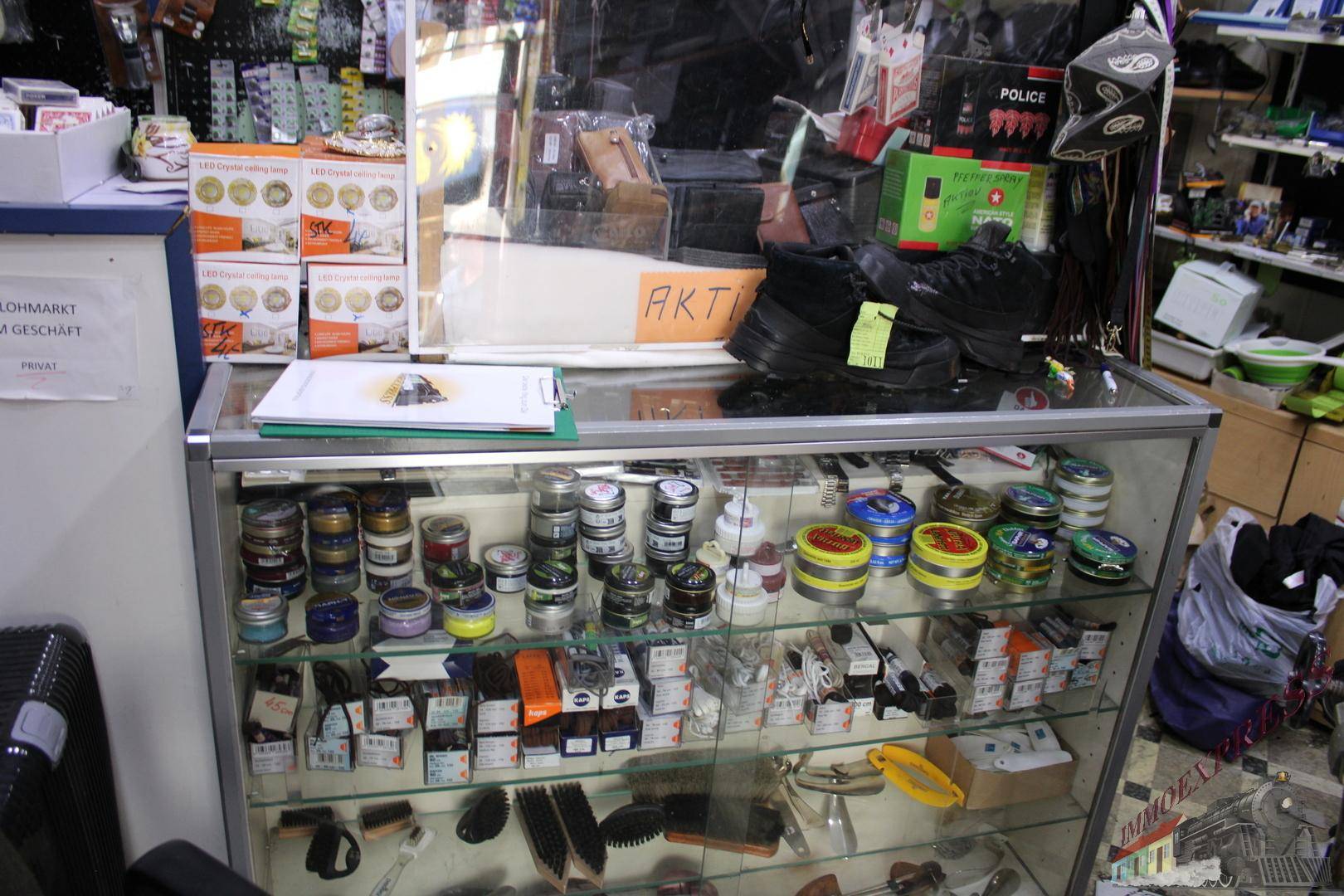 Verkaufsregal mit Glasvitrine, gefüllt mit Schuhpflegeprodukten und kleinen Artikeln für Kunden.